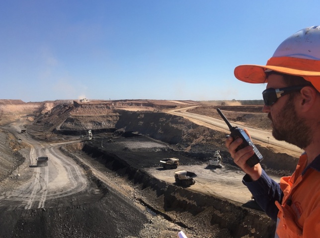 Worker using radio above open cut mine site